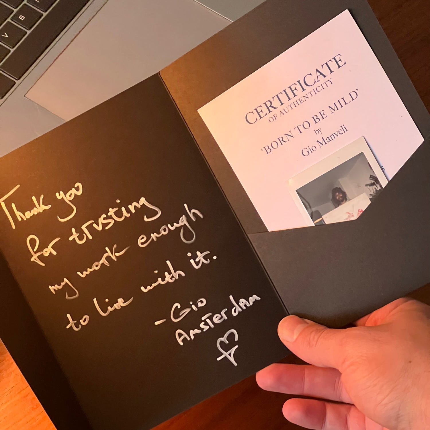 Hand holding a certificate in a black folder with handwritten text